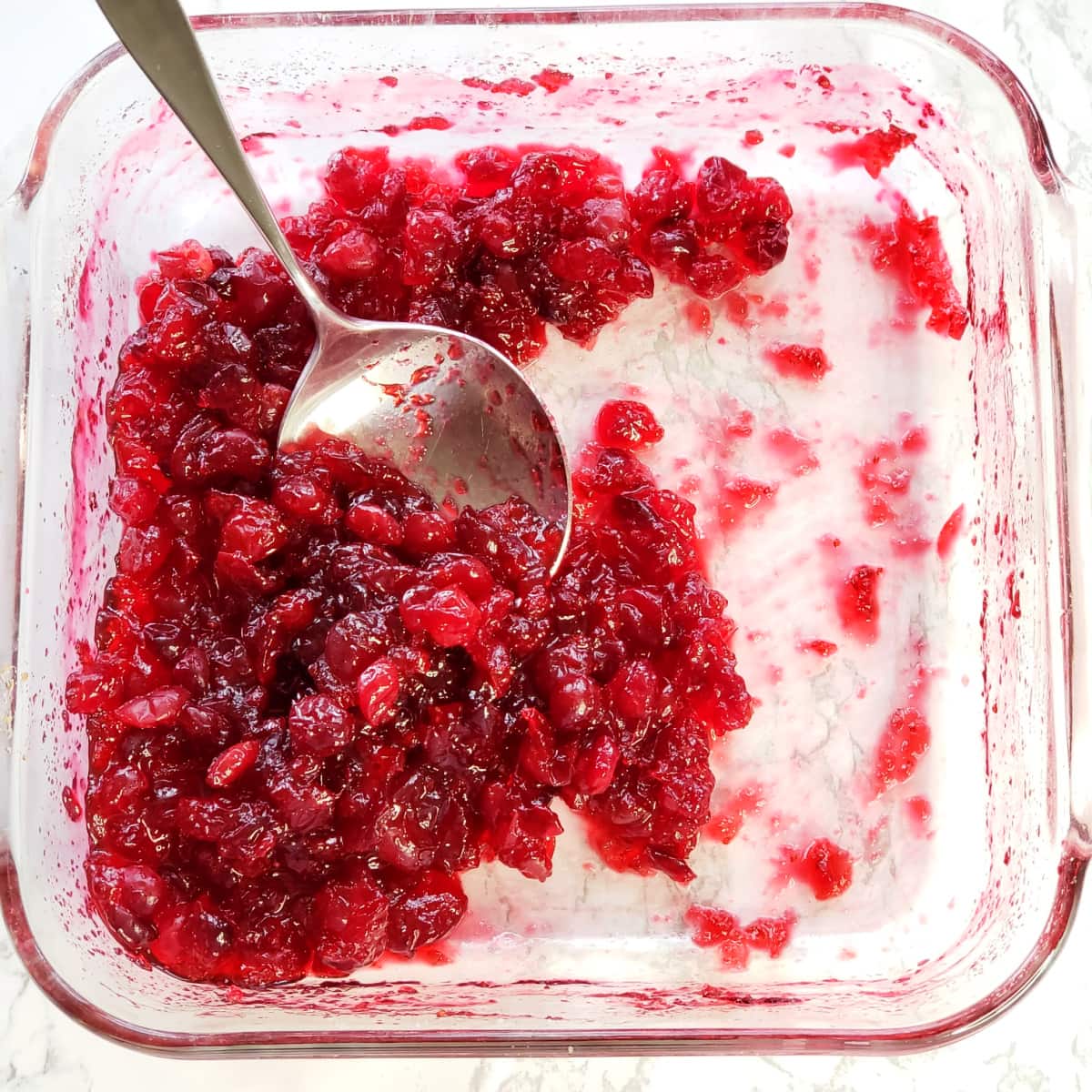 Glass baking dish with Baked Cranberry Sauce with Orange Liqueur and a big spoon