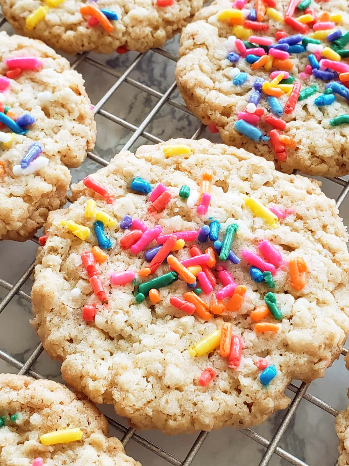Closeup of a cookie with colored sprinkles on top resting on a cooling rack
