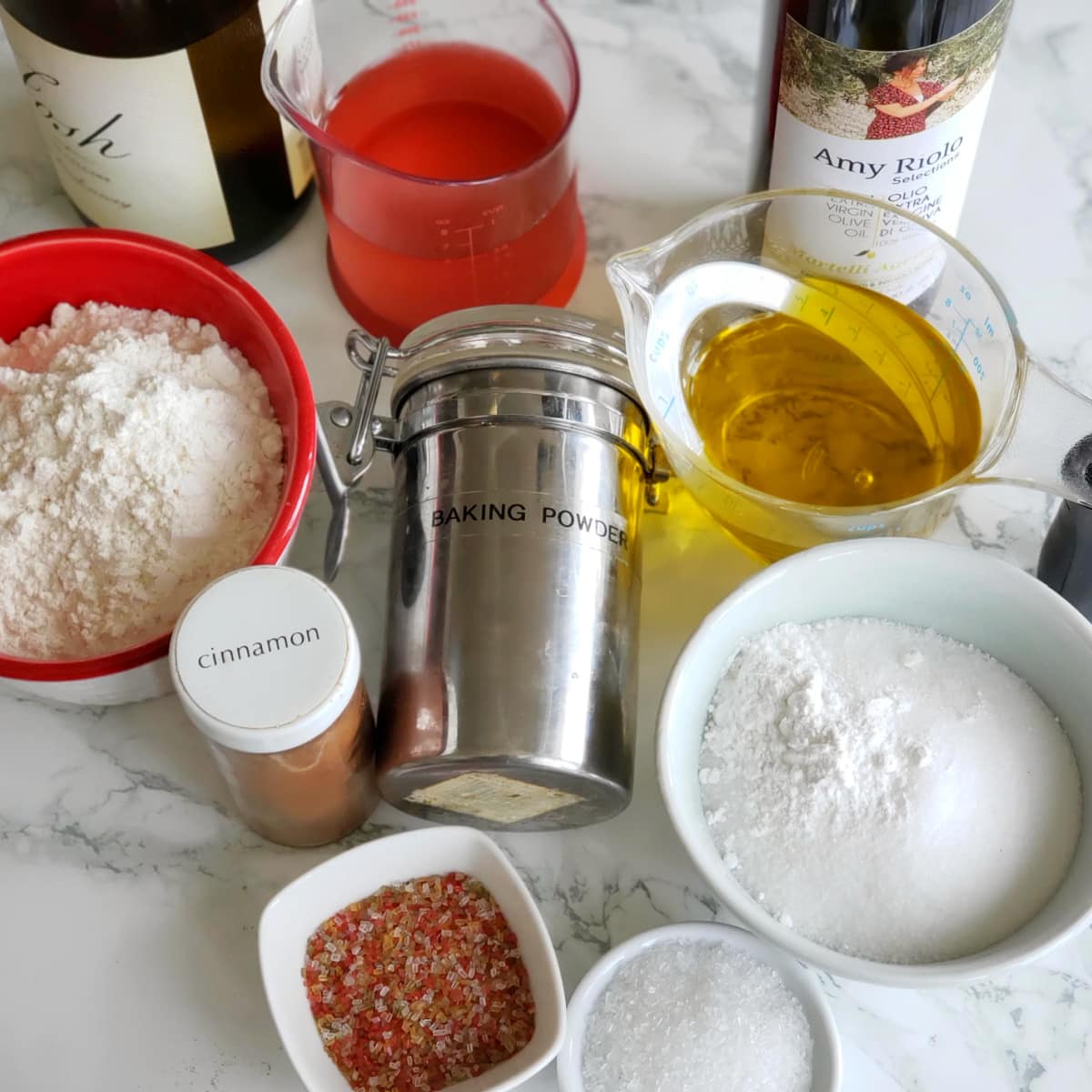 A variety of ingredients for Italian Sweet Taralli Cookies laid out on a white marble countertop