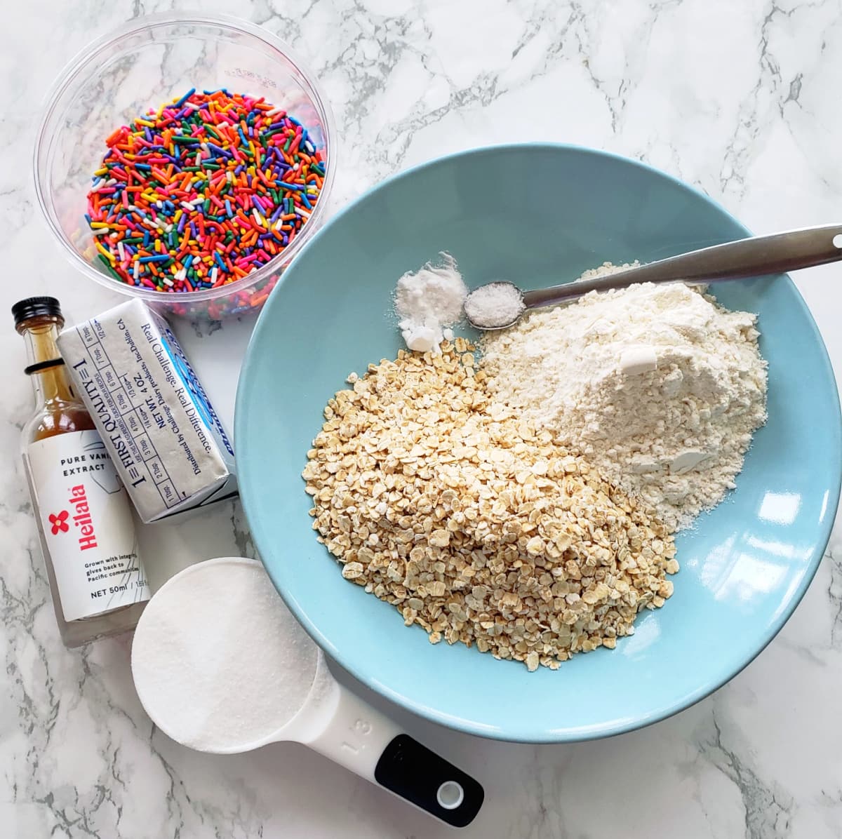 A variety of ingredients for Oatmeal Shortbread Cookies laid out on a white marble countertop
