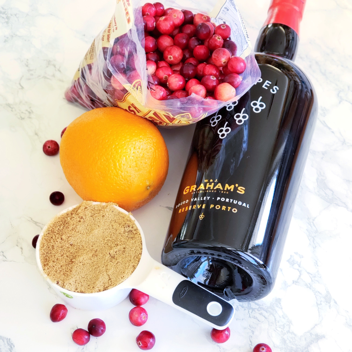 Variety of ingredients for Skillet Cranberry Sauce with Port sitting on a white marble countertop