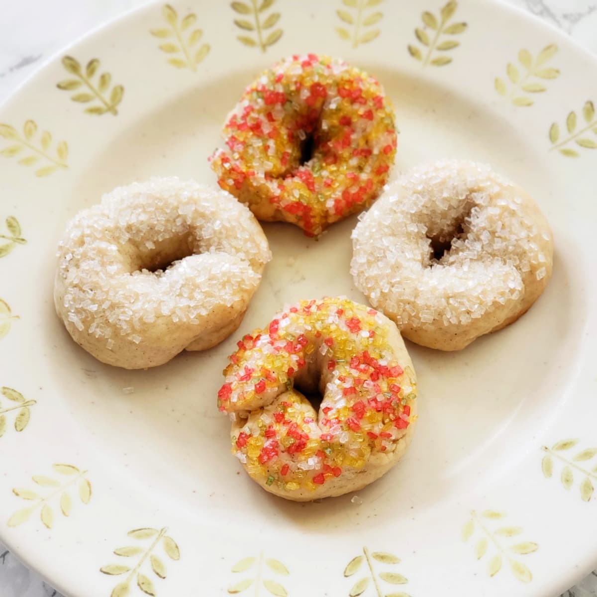 4 donut-shaped Italian Sweet Taralli Cookies on a leaf-pattered plate 
