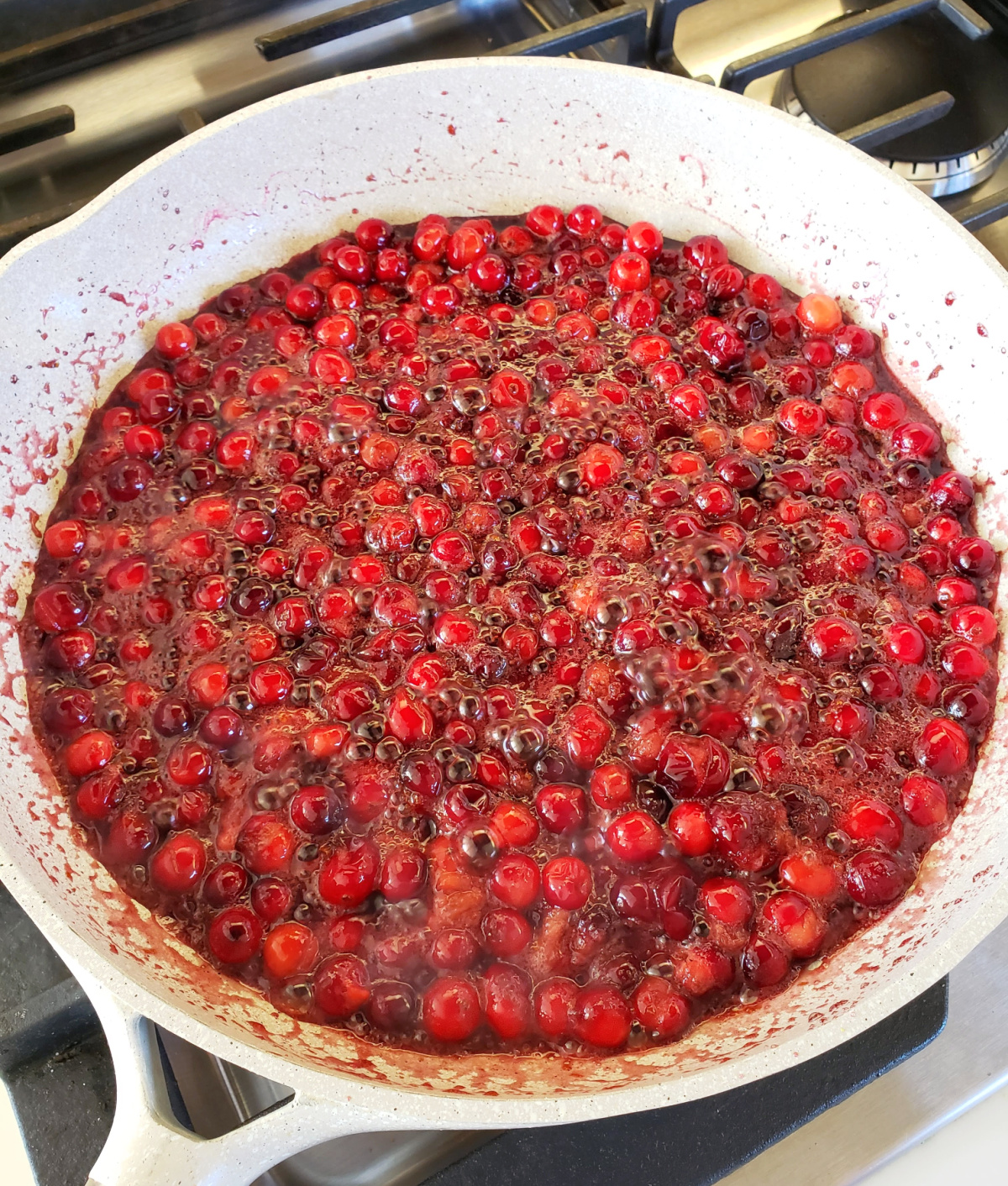 Cranberries simmer in a white skillet on ShockinglyDelicious.com