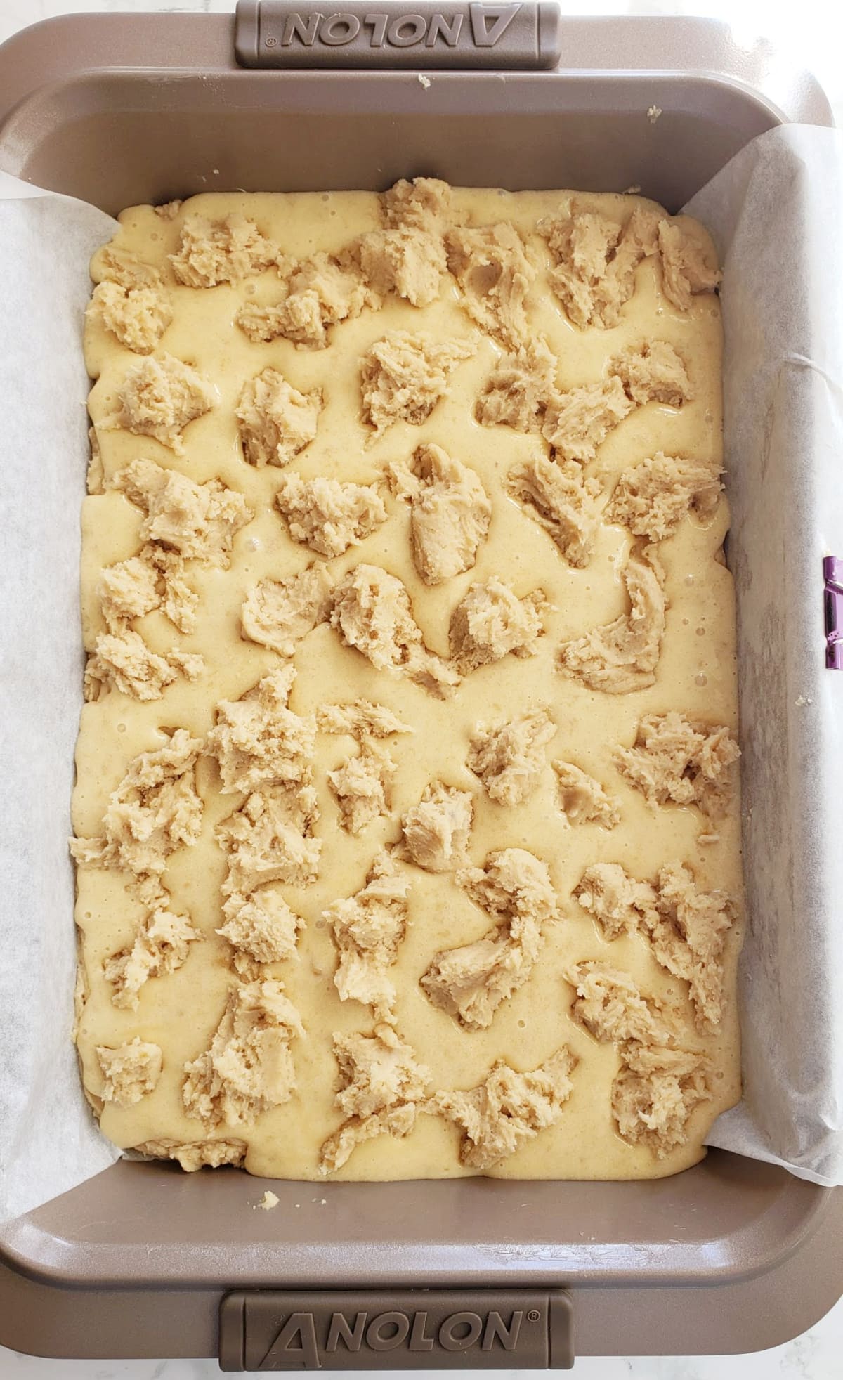 Chunks of top crust dotted over filling in gold colored baking dish