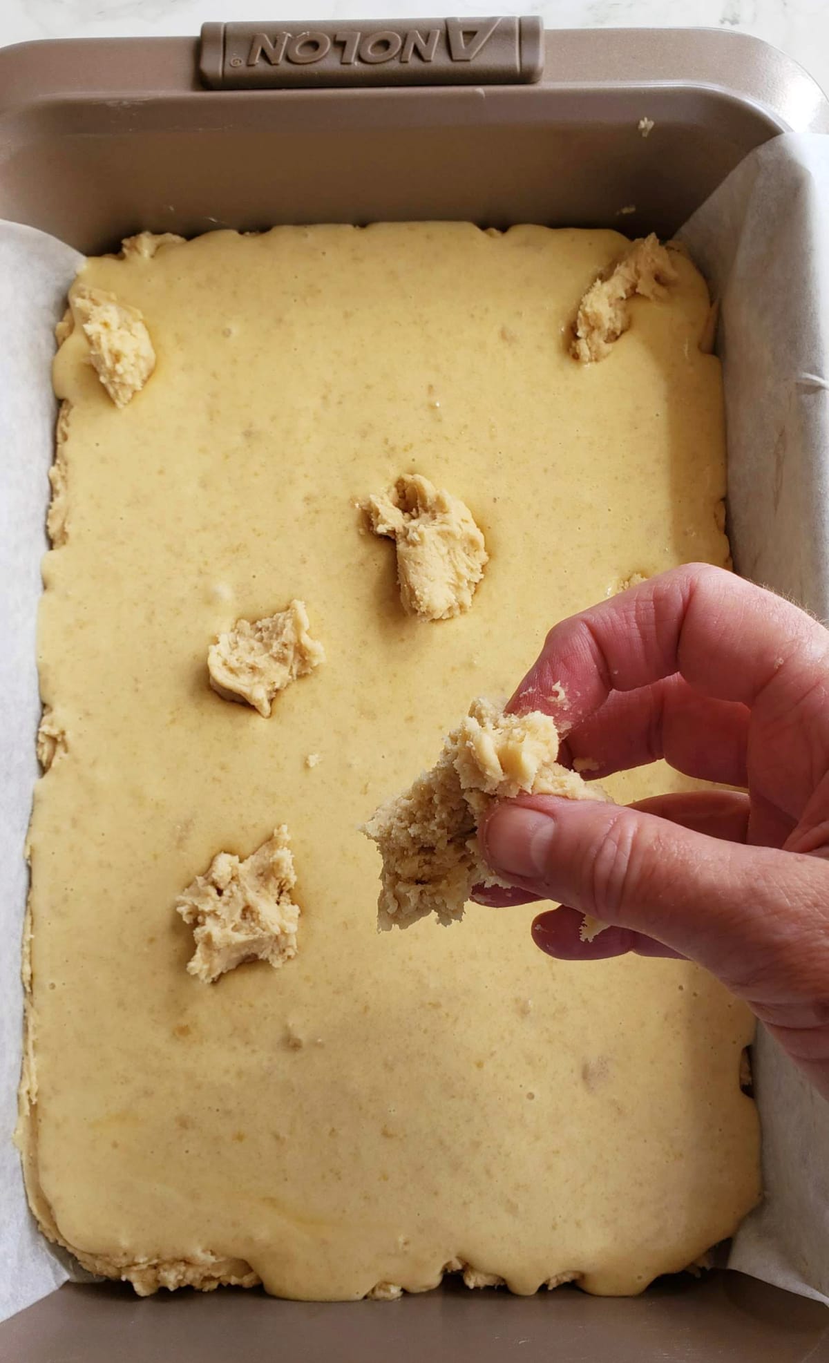 Hand separates chunks of crust over top of filling