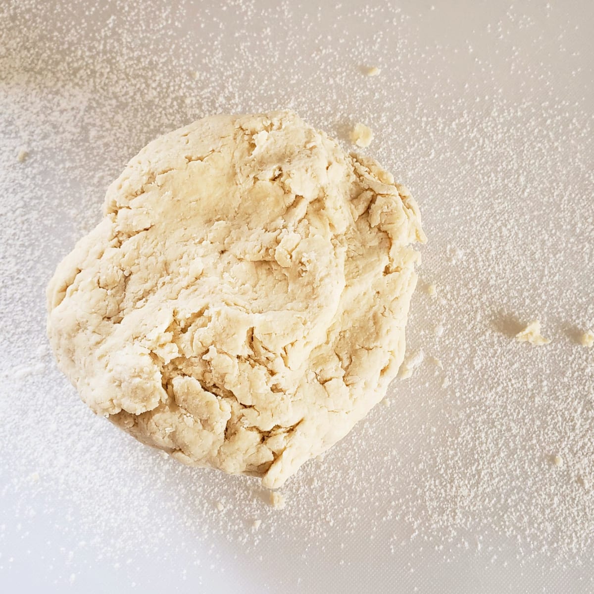 Ball of biscuit dough on a floured white cutting board