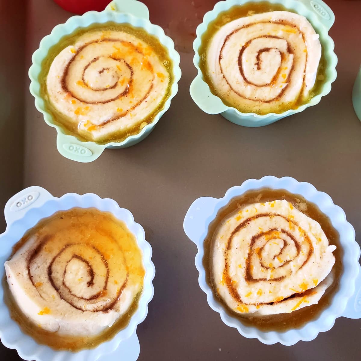 4 spiral biscuits in silicone baking cups with orange sauce over top