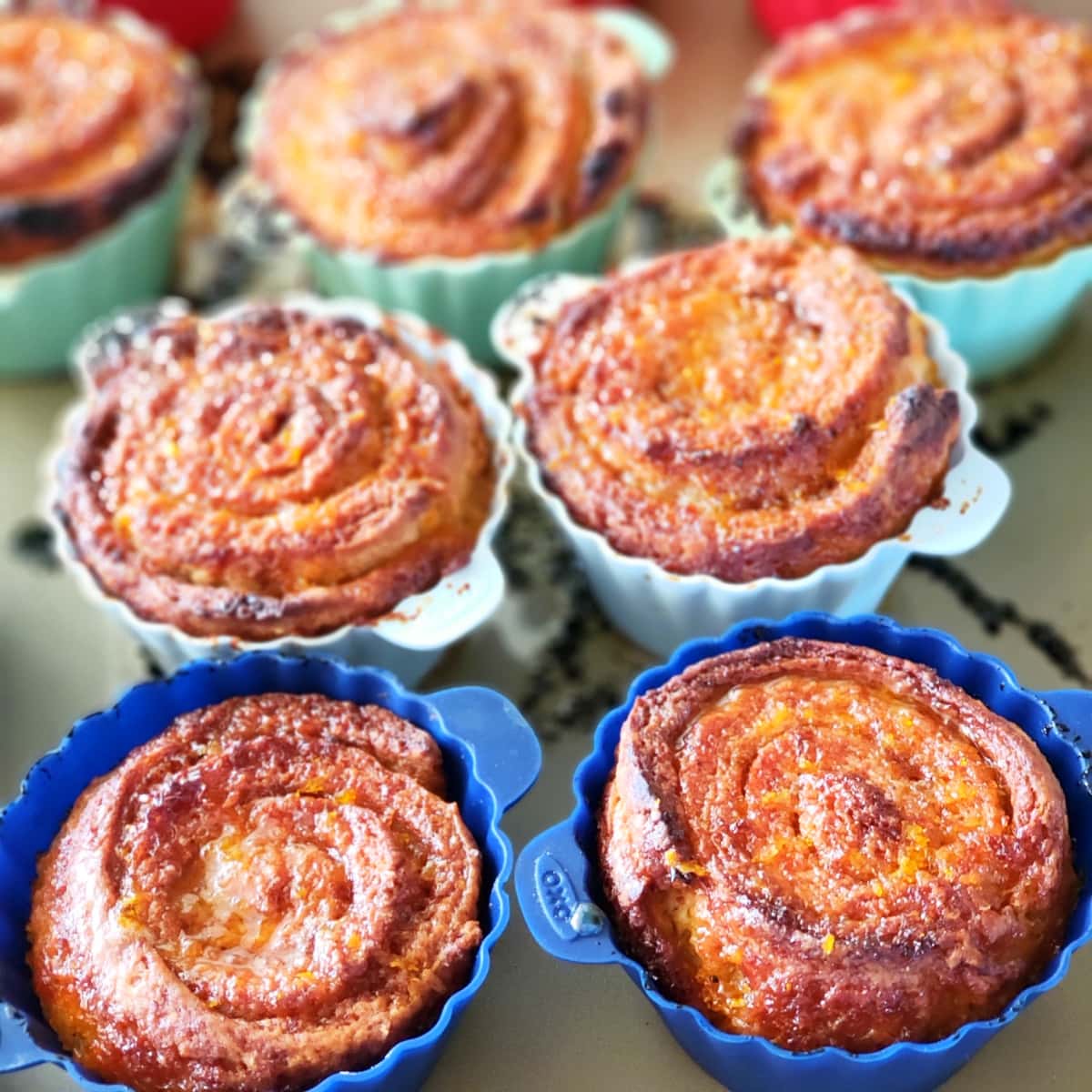 7 Sticky Spiced Orange Biscuits browned from baking, in colored silicone baking cups