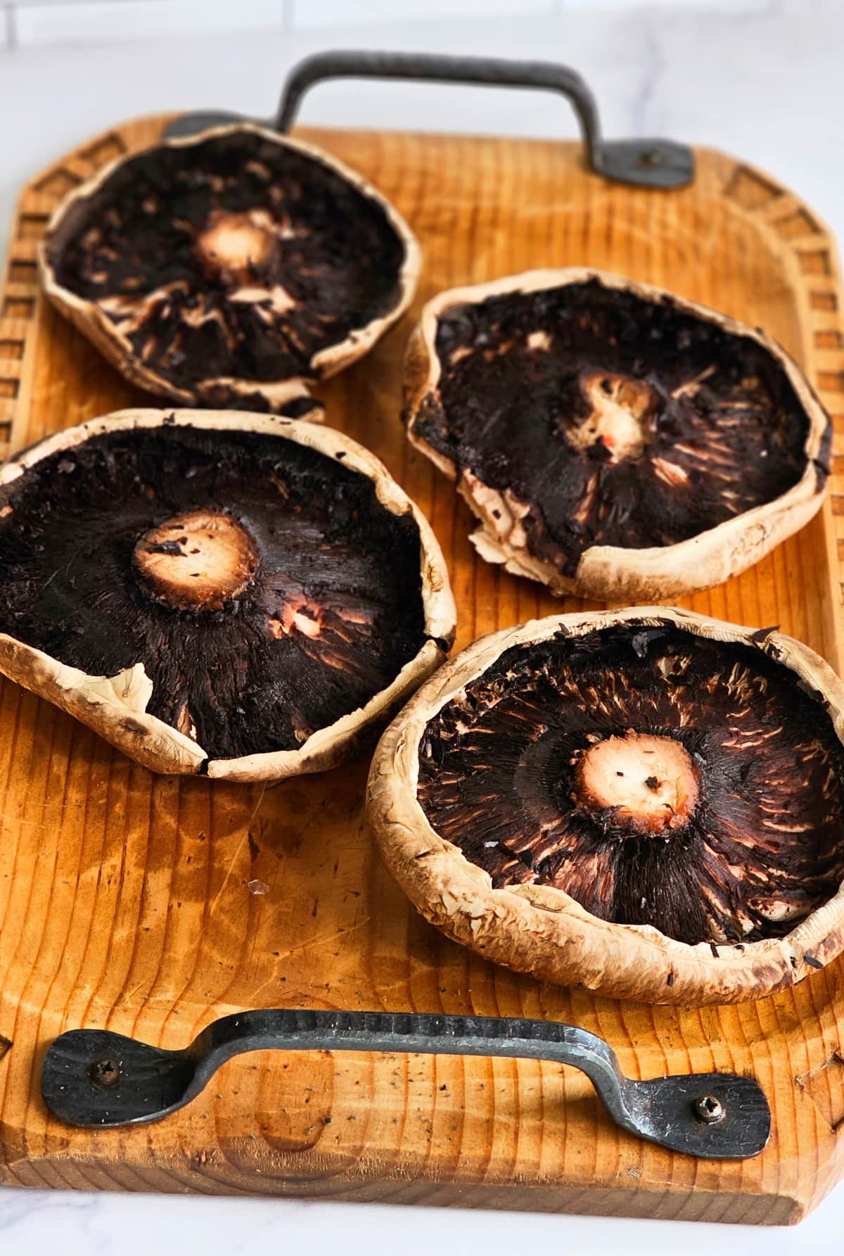 Portabella mushrooms with the gills removed on a wooden tray