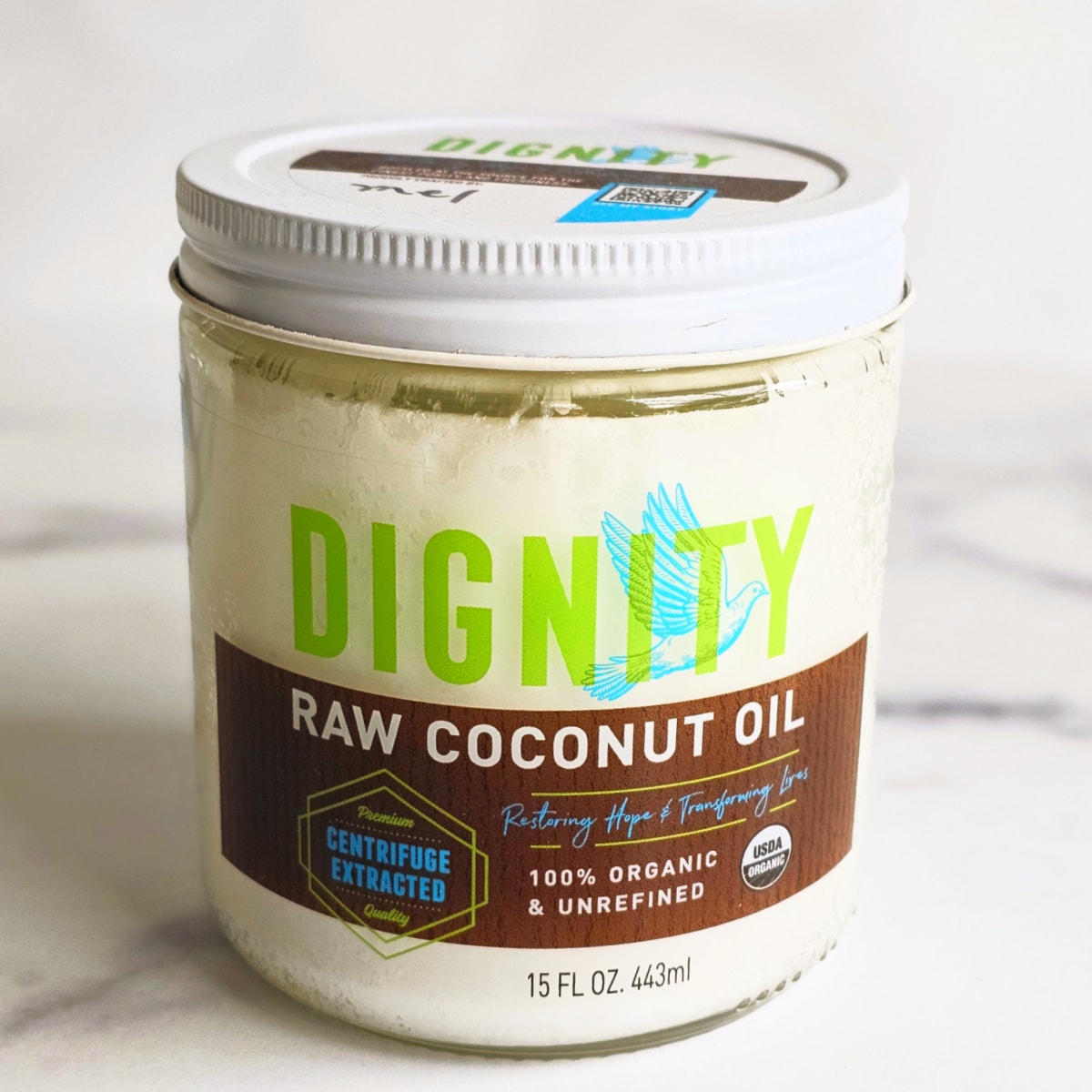 Jar of Dignity Raw Coconut Oil on a white marble counter