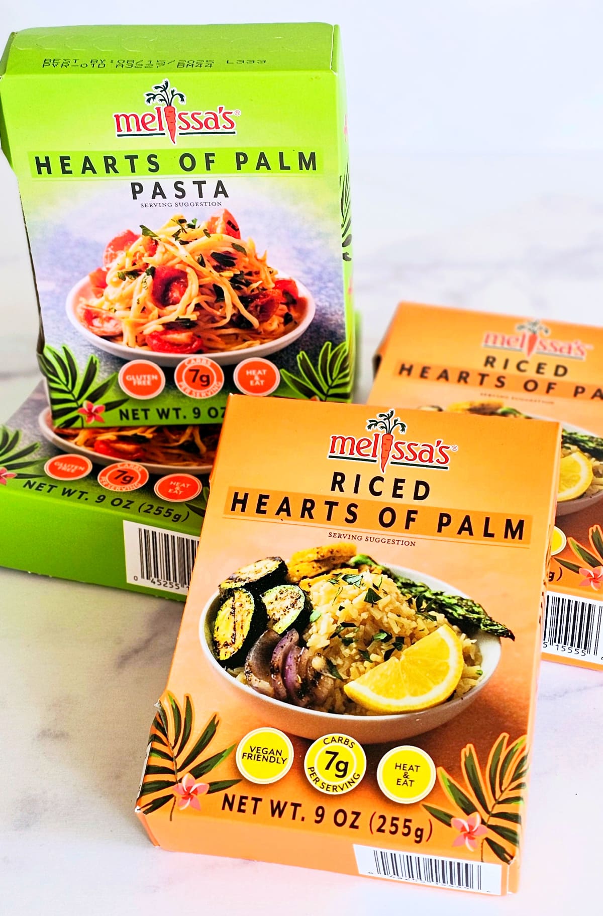 2 packages each of hearts of palm pasta and rice on a white marble counter