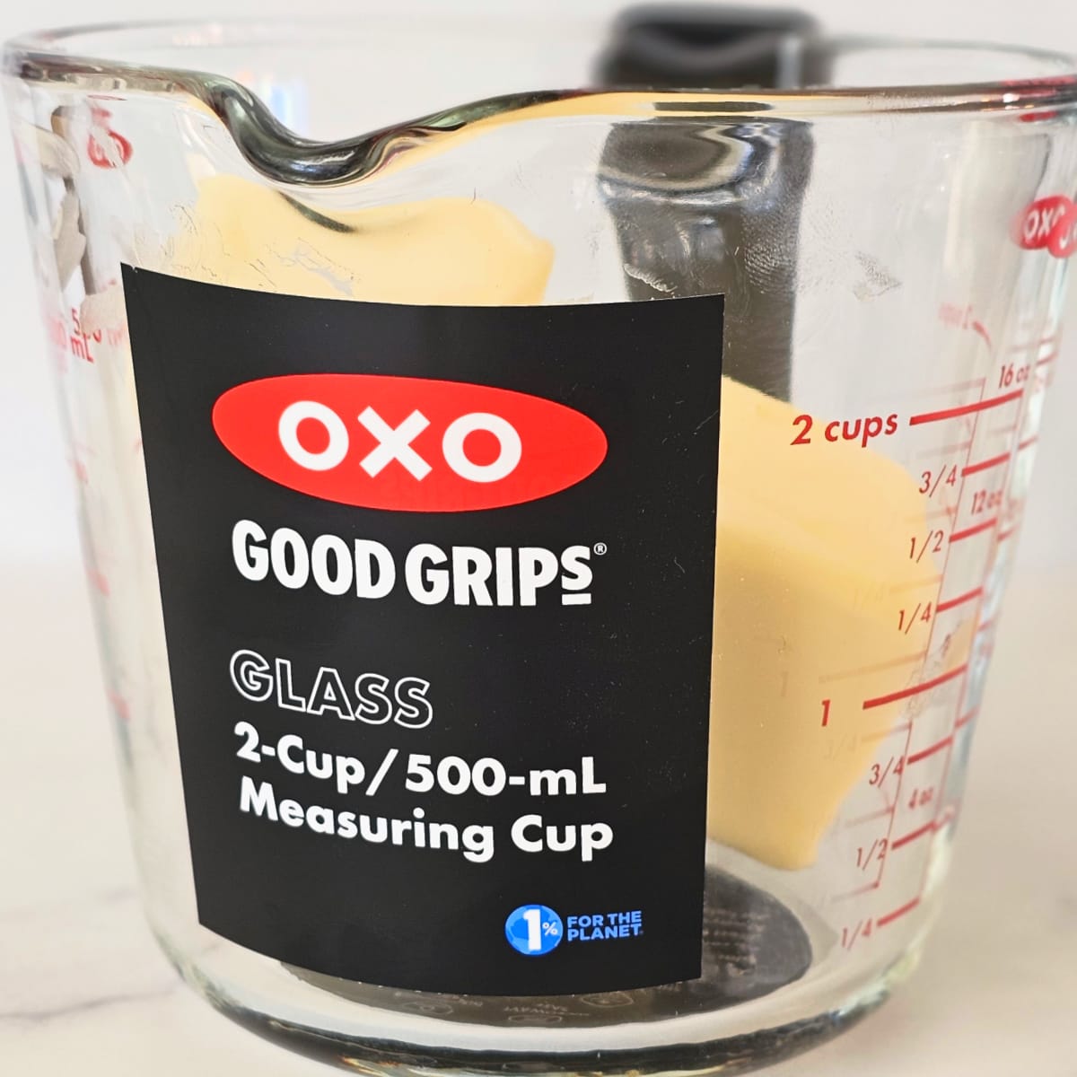 Glass measuring cup with butter inside sitting on a white counter