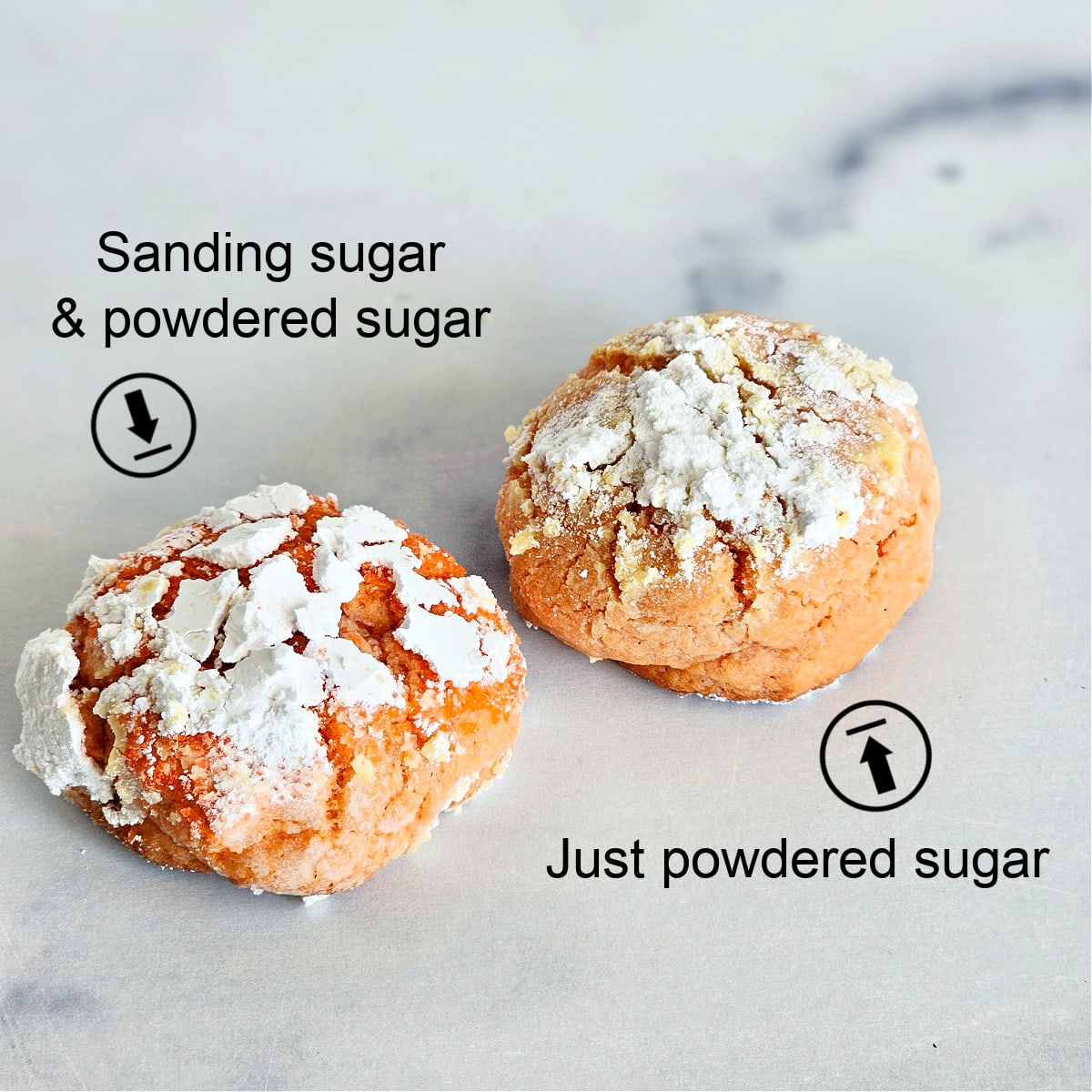 2 orange colored cookies on a white marble counter, with cracked powdered sugar on top