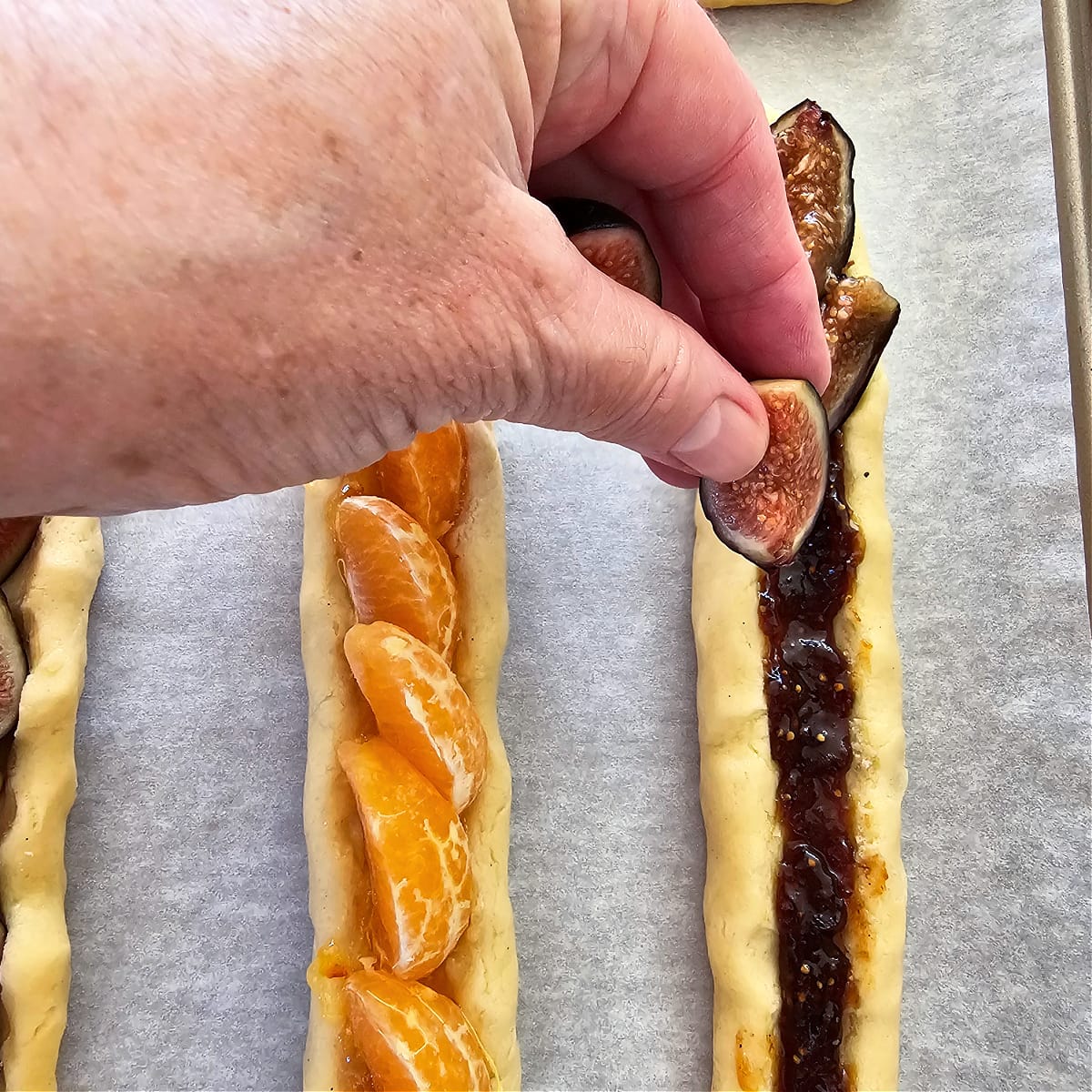 Fingers fill dough trough with fig quarters