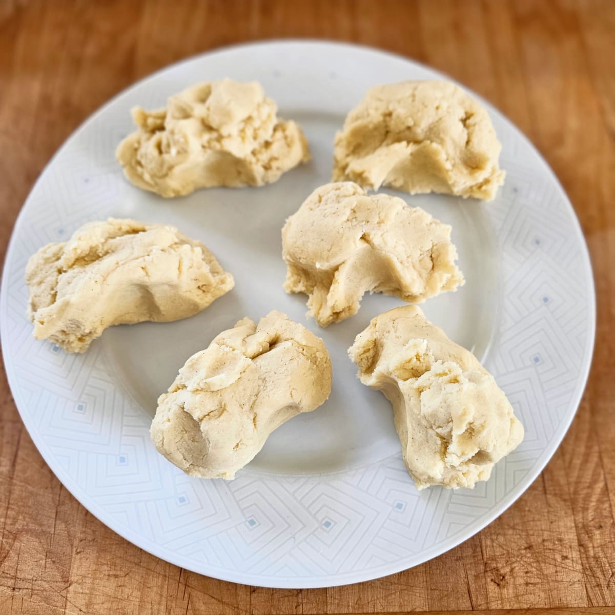 6 pieces of dough on a white plate on a wooden board