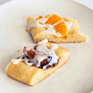 2 rectangular cookies filled with jam and fruit on a white plate