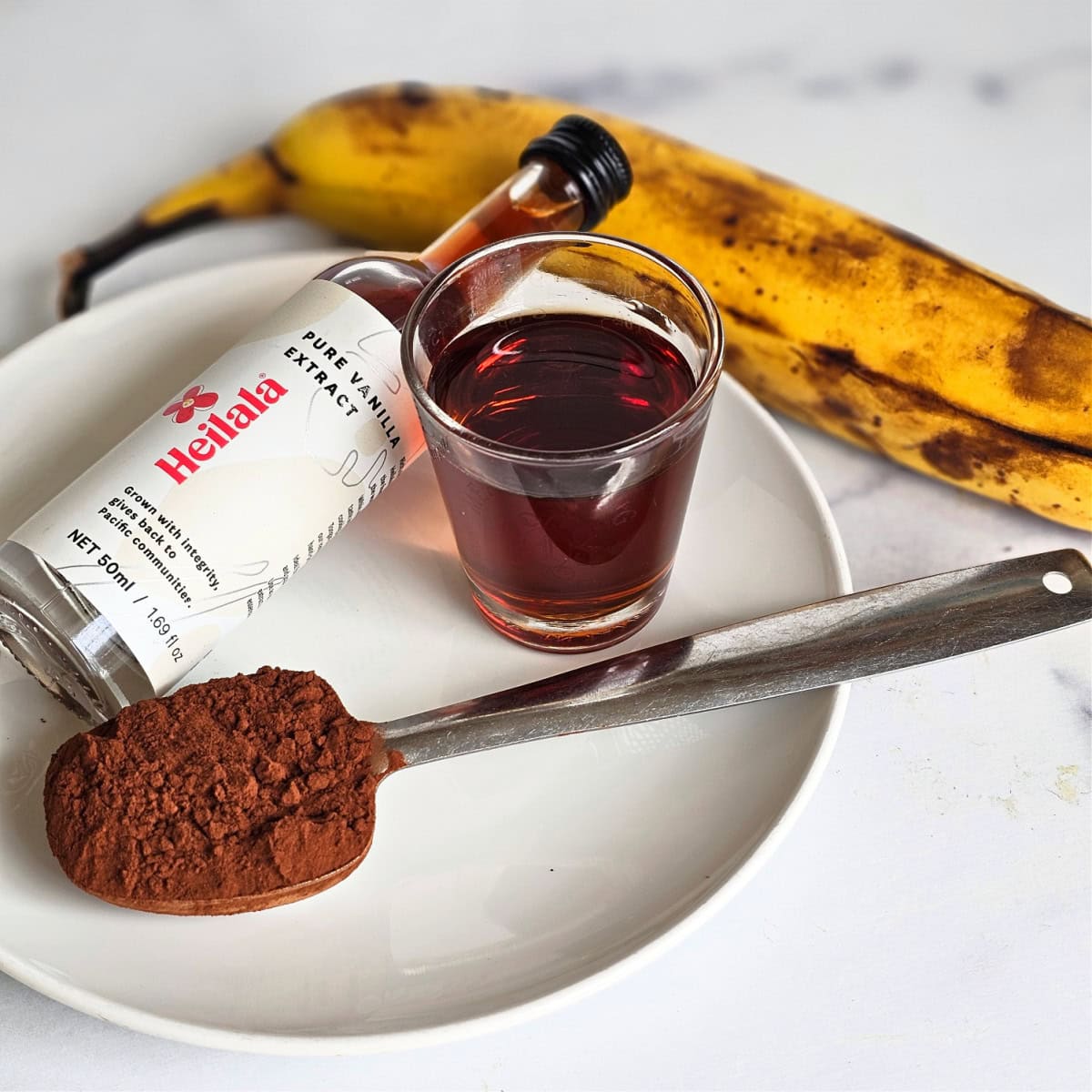 Ingredients for Vegan Chocolate Nice Cream on a white plate on a white counter