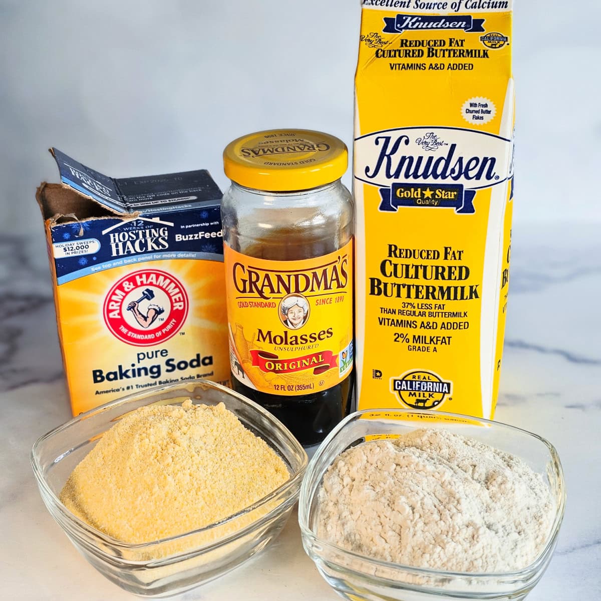 Ingredients for Molasses Cornbread set on a white marble countertop. 